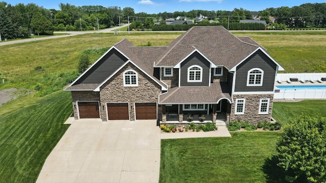 1570 Wood Duck Ln NE, Owatonna, MN 55060 - view of front of property featuring stone siding, driveway, a front yard, a garage, and covered porch
