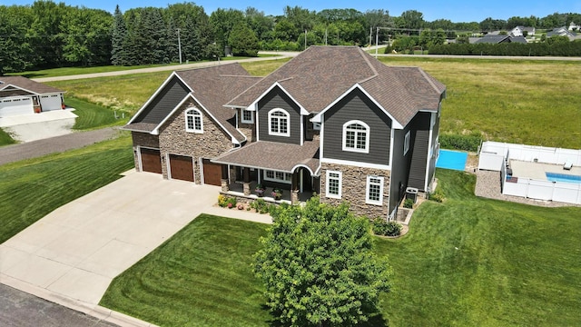 1570 Wood Duck Ln NE, Owatonna, MN 55060 - view of front of home with stone siding, driveway, a front yard, a garage, and covered porch