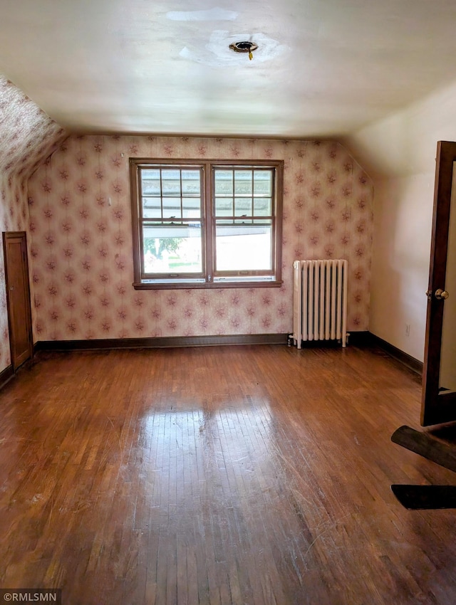 711 Main St N, Browerville, MN 56438 - bonus room featuring radiator heating unit, wallpapered walls, hardwood / wood-style flooring, and lofted ceiling