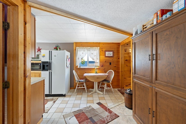 24621 Long Lake Rd, Bigfork, MN 56628 - kitchen featuring white refrigerator with ice dispenser, black microwave, light tile patterned floors, wooden walls, and light countertops