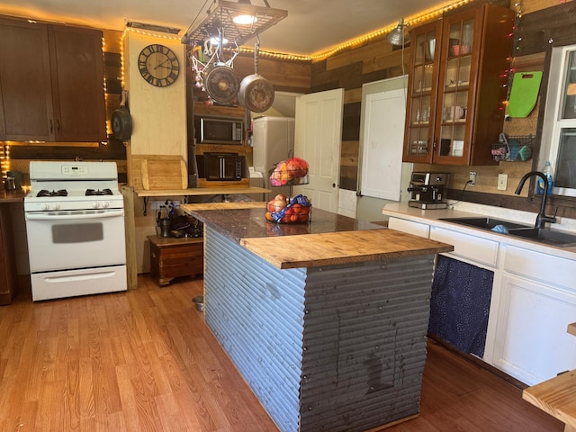 117 Maple Ave, Frazee, MN 56544 - kitchen featuring white gas stove, stainless steel microwave, light wood-type flooring, and glass insert cabinets