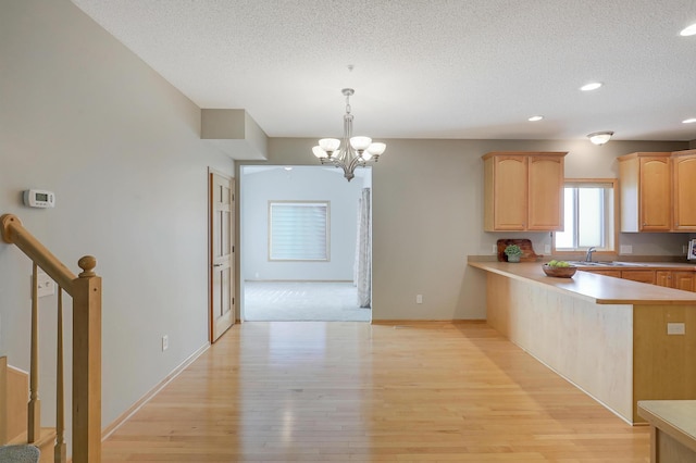 9633 Belmont Ln, Eden Prairie, MN 55347 - kitchen featuring a chandelier, a textured ceiling, light wood-style flooring, light brown cabinetry, and light countertops