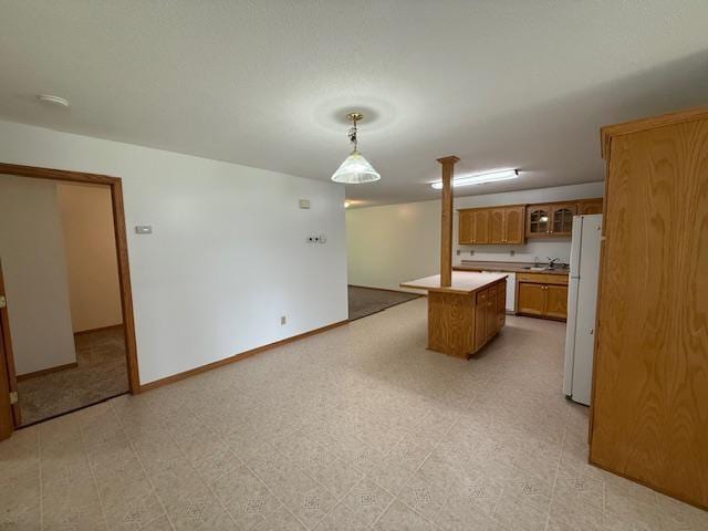 625 Meeker Ct NW, Evansville, MN 56326 - kitchen featuring a kitchen island, freestanding refrigerator, brown cabinets, light countertops, and glass insert cabinets