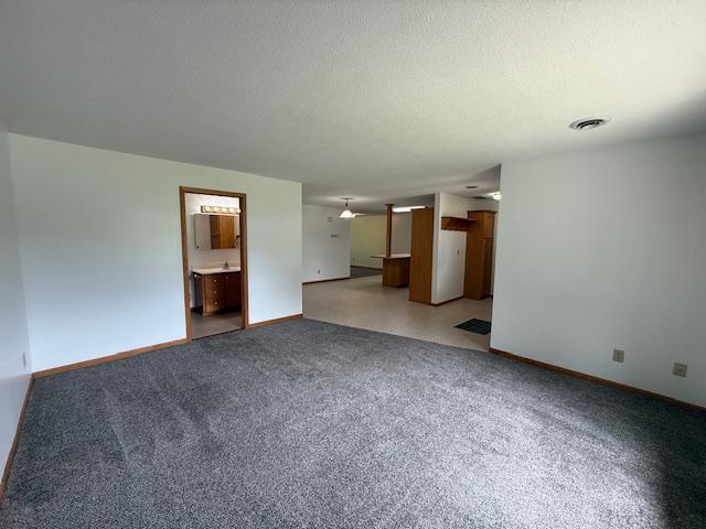 625 Meeker Ct NW, Evansville, MN 56326 - unfurnished living room with baseboards and light colored carpet