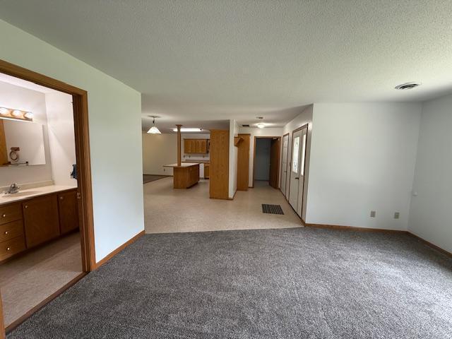 625 Meeker Ct NW, Evansville, MN 56326 - unfurnished living room with a textured ceiling and light carpet