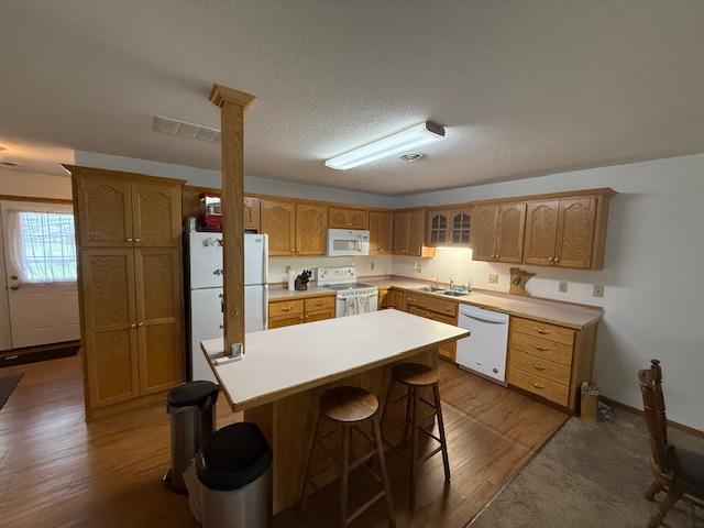 625 Meeker Ct NW, Evansville, MN 56326 - kitchen featuring white appliances, dark wood-type flooring, a breakfast bar area, a center island, and light countertops