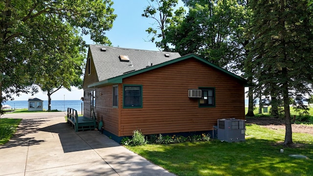 15467 Twilight Rd, Onamia, MN 56359 - view of property exterior featuring a lawn, a wall mounted AC, roof with shingles, and a water view