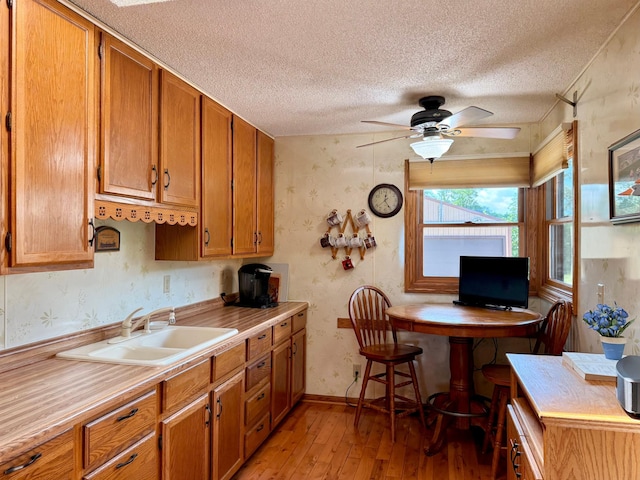 15467 Twilight Rd, Onamia, MN 56359 - kitchen with light wood-type flooring, a textured ceiling, brown cabinetry, light countertops, and a ceiling fan