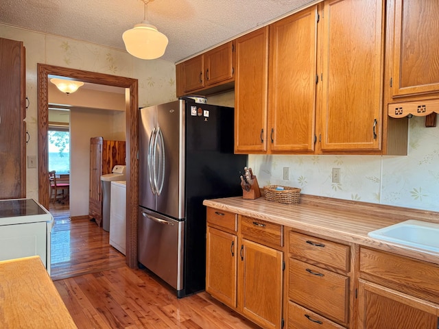 15467 Twilight Rd, Onamia, MN 56359 - kitchen featuring wallpapered walls, freestanding refrigerator, light wood-style flooring, stove, and light countertops