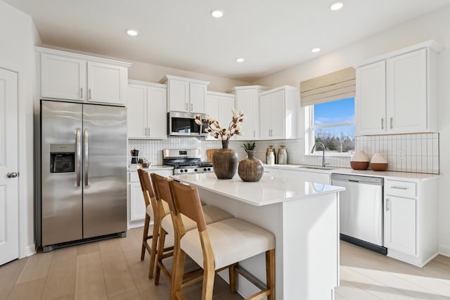 18695 Kennedy St NW, Elk River, MN 55330 - kitchen with appliances with stainless steel finishes, a kitchen island, white cabinetry, and recessed lighting