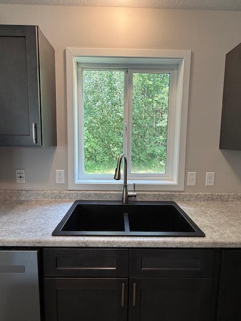 1312 Natures Trl, Alexandria, MN 56308 - kitchen featuring dishwasher, light countertops, dark cabinetry, and a textured ceiling