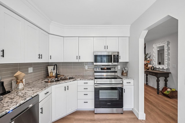 1575 Wayzata Blvd Unit A, Long Lake, MN 55356 - kitchen featuring appliances with stainless steel finishes, light wood finished floors, light stone countertops, tasteful backsplash, and white cabinetry