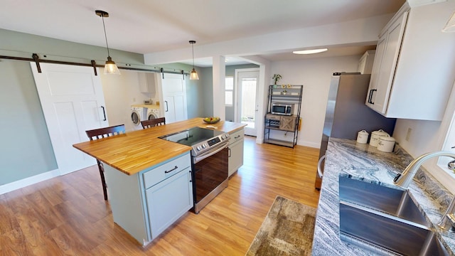 410 Atlantic Ave W, Grove City, MN 56243 - kitchen featuring a barn door, appliances with stainless steel finishes, washer and dryer, a breakfast bar, and butcher block counters