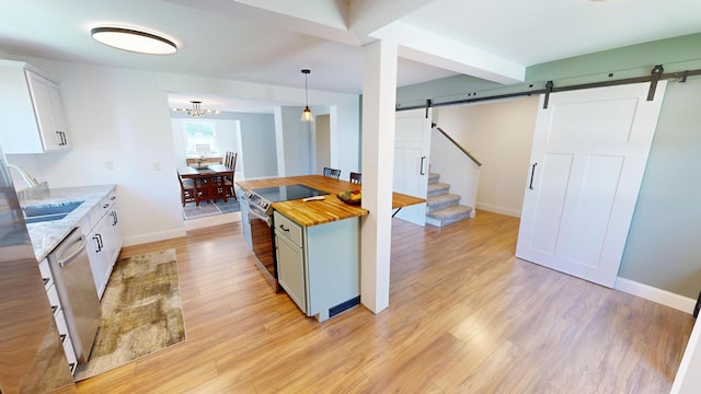 410 Atlantic Ave W, Grove City, MN 56243 - kitchen with a barn door, appliances with stainless steel finishes, wood counters, light wood finished floors, and hanging light fixtures