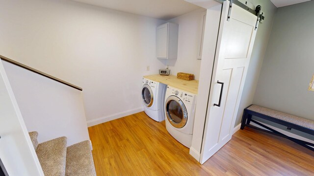 410 Atlantic Ave W, Grove City, MN 56243 - laundry area featuring washing machine and dryer, light wood-style floors, a barn door, and cabinet space