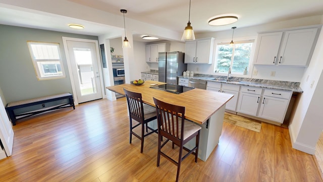 410 Atlantic Ave W, Grove City, MN 56243 - kitchen featuring appliances with stainless steel finishes, a kitchen breakfast bar, hanging light fixtures, and light wood-type flooring