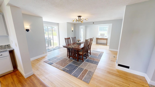 410 Atlantic Ave W, Grove City, MN 56243 - dining room featuring a chandelier, light wood-style floors, healthy amount of natural light, and a textured ceiling