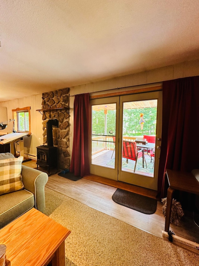 1414 E Shore Dr, Edgewater, WI 54817 - living room featuring a textured ceiling, wood finished floors, a wood stove, and a baseboard radiator