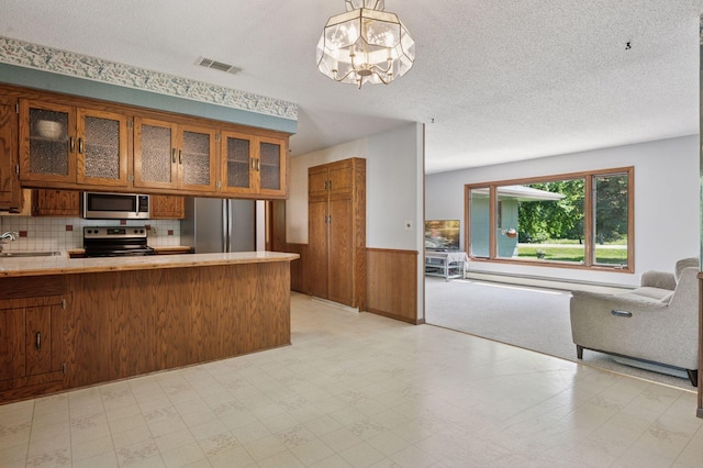 29908 108th St NW, Baldwin Twp, MN 55371 - kitchen with stainless steel appliances, brown cabinets, wainscoting, open floor plan, and light floors