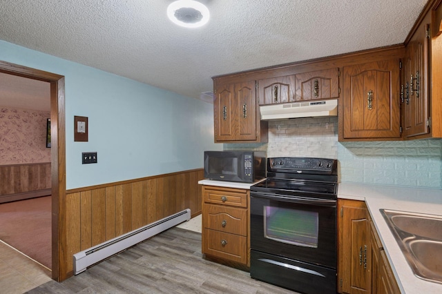 29908 108th St NW, Baldwin Twp, MN 55371 - kitchen with black appliances, a baseboard radiator, under cabinet range hood, wainscoting, and a textured ceiling