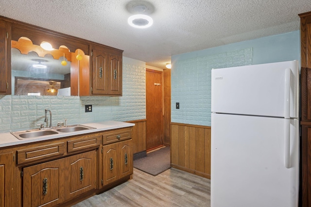 29908 108th St NW, Baldwin Twp, MN 55371 - kitchen with freestanding refrigerator, light wood finished floors, a textured ceiling, brown cabinetry, and light countertops