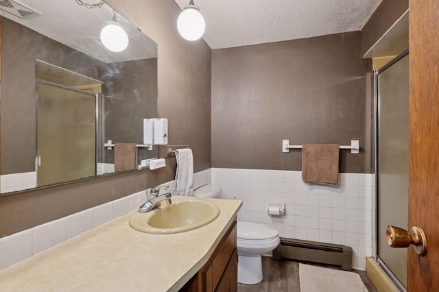 29908 108th St NW, Baldwin Twp, MN 55371 - bathroom featuring a baseboard heating unit, a stall shower, vanity, a textured ceiling, and tile walls
