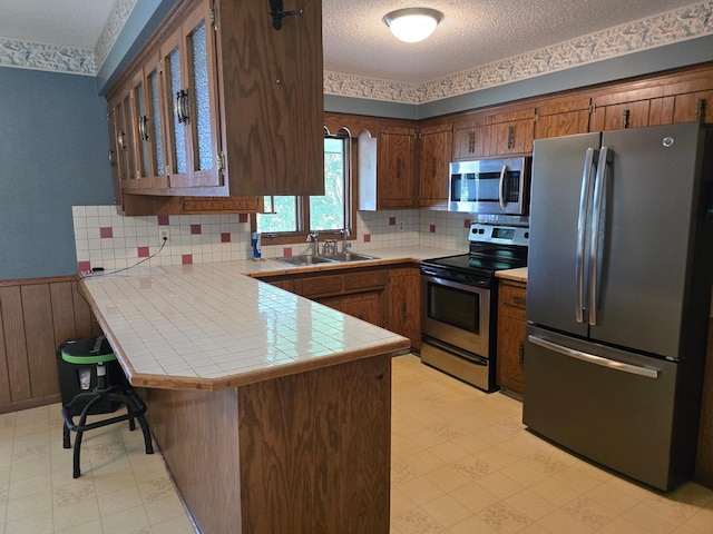 29908 108th St NW, Baldwin Twp, MN 55371 - kitchen featuring appliances with stainless steel finishes, a peninsula, light floors, a textured ceiling, and glass insert cabinets