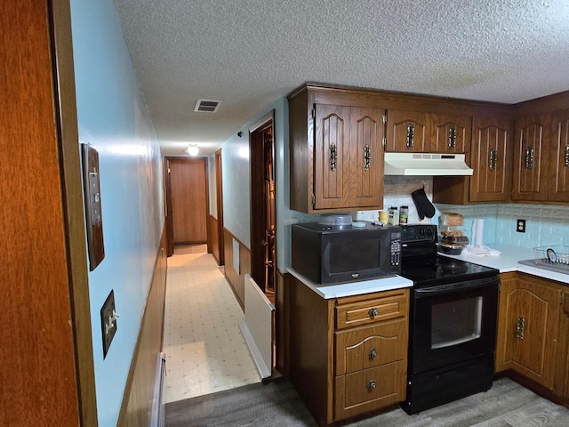 29908 108th St NW, Baldwin Twp, MN 55371 - kitchen featuring black appliances, under cabinet range hood, a textured ceiling, light countertops, and brown cabinets