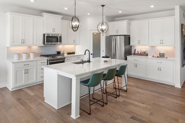 14643 107th Pl N, Maple Grove, MN 55369 - kitchen with appliances with stainless steel finishes, backsplash, an island with sink, a breakfast bar, and white cabinets