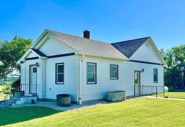 1555 US Highway 75, Lake Benton Twp, MN 56149 - rear view of house with board and batten siding, roof with shingles, a chimney, and a yard