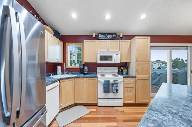 817 16th Avenue Ct W, West Fargo, ND 58078 - kitchen featuring white appliances, light brown cabinetry, light wood finished floors, a textured ceiling, and dark countertops