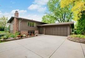 6727 80th Ave N, Brooklyn Park, MN 55445 - view of front of house with concrete driveway, a garage, and a chimney