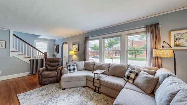 236 Alleghany Ave, Wabasha, MN 55981 - living area featuring arched walkways, radiator, wood finished floors, stairs, and crown molding