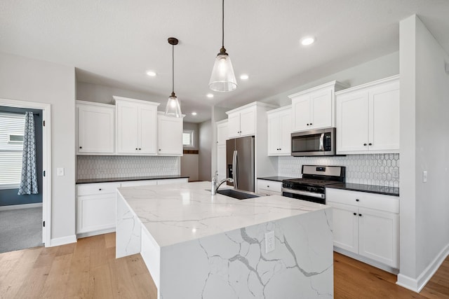 14221 Aspen Ave, Rosemount, MN 55068 - kitchen featuring appliances with stainless steel finishes, light wood finished floors, a kitchen island with sink, backsplash, and white cabinets