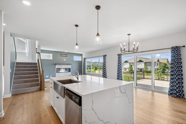 14221 Aspen Ave, Rosemount, MN 55068 - kitchen with dishwasher, a glass covered fireplace, light wood-style floors, white cabinetry, and hanging light fixtures