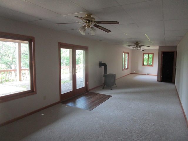 32468 County Highway 27, Elizabeth Twp, MN 56534 - unfurnished living room featuring a wood stove, carpet flooring, healthy amount of natural light, a drop ceiling, and a ceiling fan