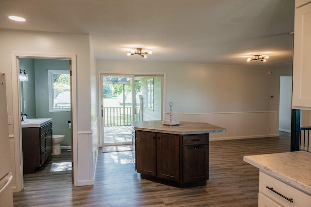 600 Venn St, Sherburn, MN 56171 - kitchen with dark wood-type flooring, dark brown cabinetry, a wainscoted wall, light countertops, and a kitchen island