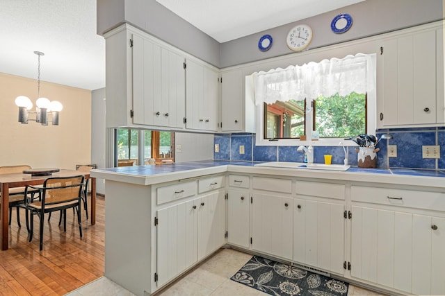 6670 Maple Dr, Rockford, MN 55373 - kitchen featuring a chandelier, decorative backsplash, a peninsula, and white cabinetry