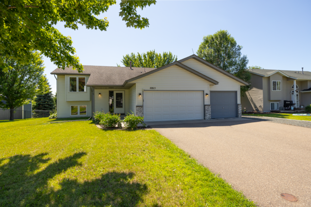 10815 Matthew Dr, Chisago City, MN 55013 - tri-level home with asphalt driveway, an attached garage, a front lawn, and a shingled roof