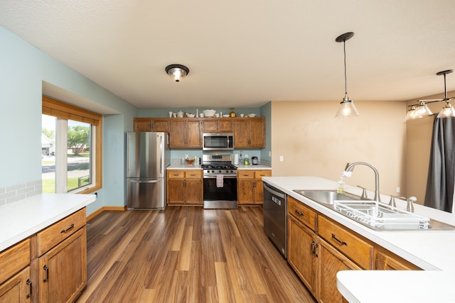 10815 Matthew Dr, Chisago City, MN 55013 - kitchen featuring appliances with stainless steel finishes, dark wood-style floors, light countertops, brown cabinets, and hanging light fixtures
