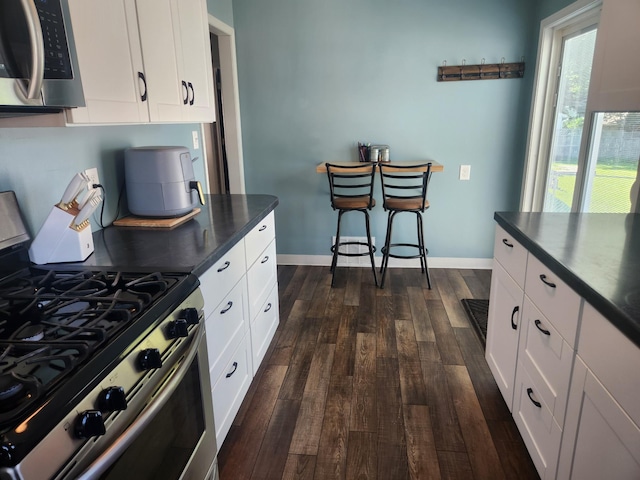 1302 Clark St, Albert Lea, MN 56007 - kitchen featuring stainless steel appliances, dark countertops, dark wood-style flooring, and white cabinetry