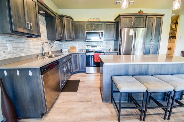 412 Hampton Dr W, Moorhead, MN 56560 - kitchen featuring stainless steel appliances, tasteful backsplash, a breakfast bar area, light wood-style flooring, and light countertops