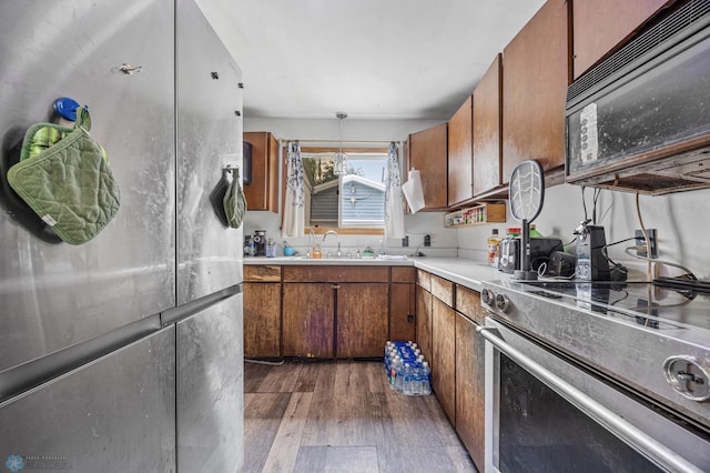 1330 16 1/2 St S, Fargo, ND 58103 - kitchen with stainless steel electric range oven, black microwave, dark wood-style floors, and brown cabinetry