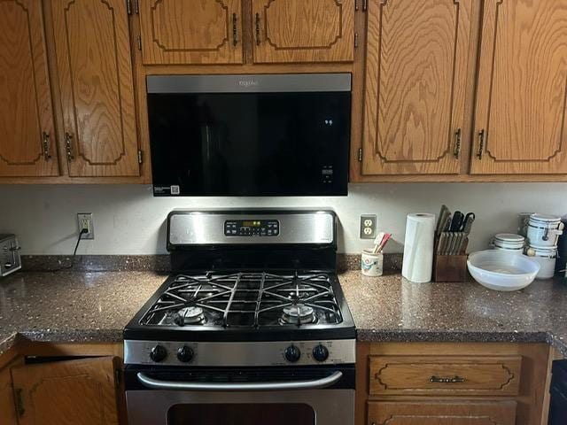 3324 131st Ln NW, Coon Rapids, MN 55448 - kitchen featuring stainless steel range with gas stovetop, brown cabinets, and dark stone counters
