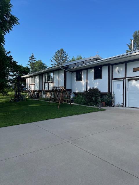 670 23rd Ave NE, Sauk Rapids, MN 56379 - view of front of house with an attached garage, driveway, a front lawn, and stucco siding