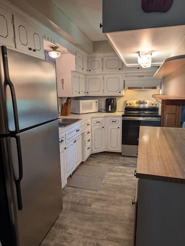 670 23rd Ave NE, Sauk Rapids, MN 56379 - kitchen with stainless steel appliances, white cabinetry, dark wood-style flooring, range hood, and a textured ceiling