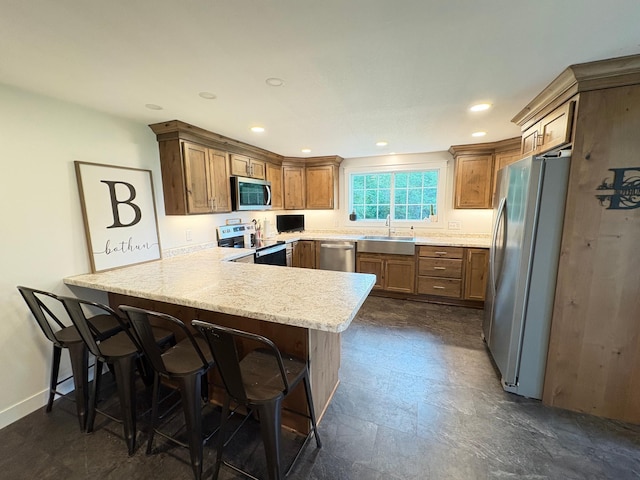 2812 150th St, Maxwell Twp, MN 56232 - kitchen featuring stainless steel appliances, a peninsula, brown cabinetry, a breakfast bar area, and recessed lighting