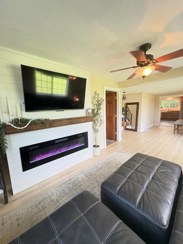 2812 150th St, Maxwell Twp, MN 56232 - living room with a glass covered fireplace, wood finished floors, a ceiling fan, and a textured ceiling