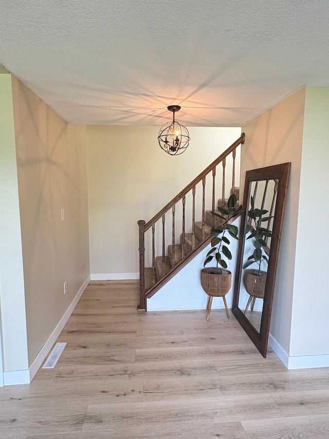 2812 150th St, Maxwell Twp, MN 56232 - stairs featuring a chandelier, wood finished floors, and a textured ceiling