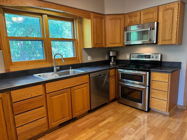 14158 185th Ave NE, Smiley Twp, MN 56701 - kitchen featuring appliances with stainless steel finishes, light wood-style flooring, dark countertops, and brown cabinetry